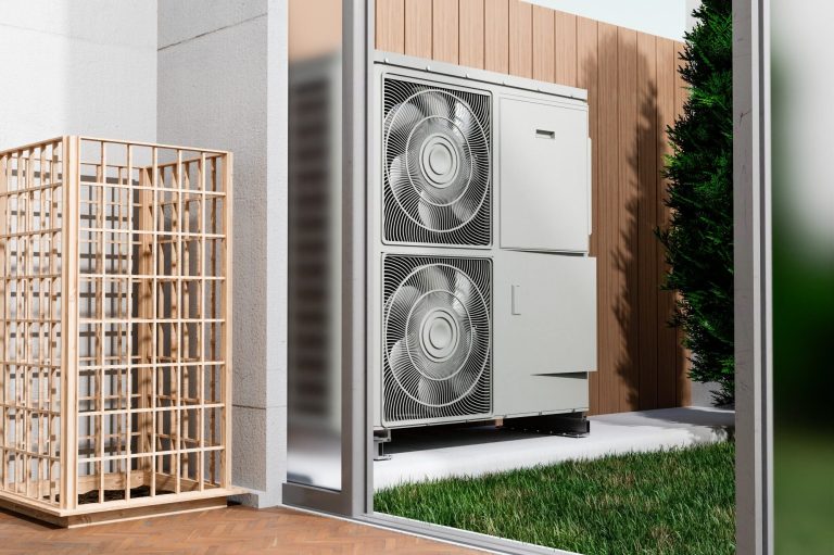 Climatiseur à l'extérieur, avec un espace vert en arrière-plan et une clôture en bois.