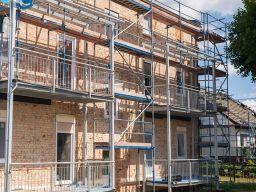 Échafaudage en acier autour d'un bâtiment en briques pour travaux de rénovation.
